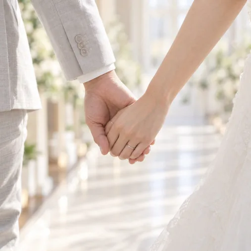 結婚式の会場で、新郎新婦が手をつないで歩いている手元