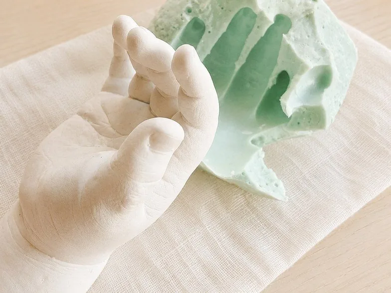 固まった白い石こうの手型を、ミント色の型から抜き出したところ