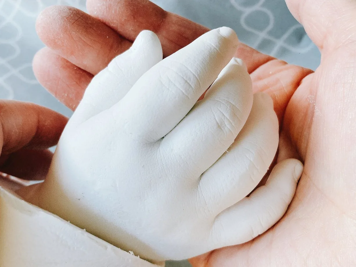完成した白い手型を、大人が両手で持っている様子