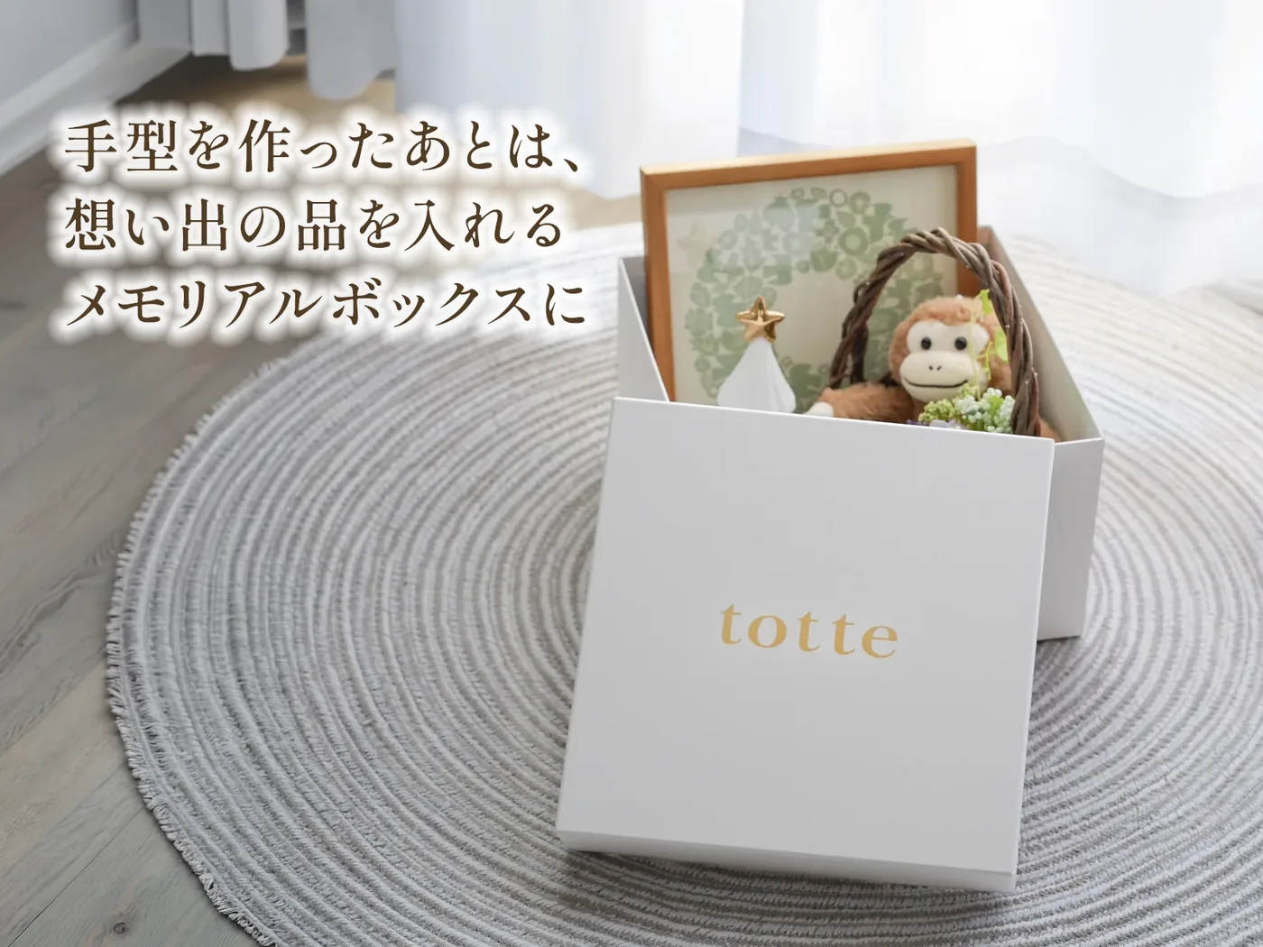 手型を作ったあとは、想い出の品を入れるメモリアルボックスに。ふたを開けた白いtotteの箱に、写真立てやぬいぐるみを入れている様子