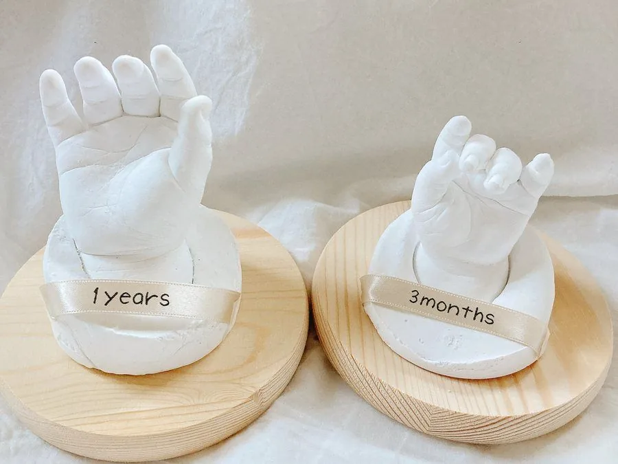 「3months」と「1years」のリボンを巻いた手型が、白木の台座の上に並んでいる様子